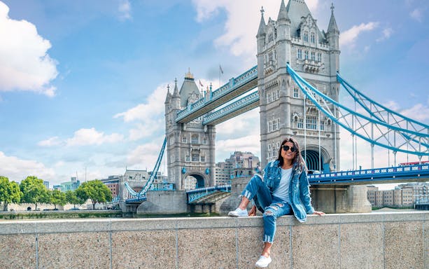 Tower Bridge over River Thames in London with a person sitting on a wall, part of Go City tour.