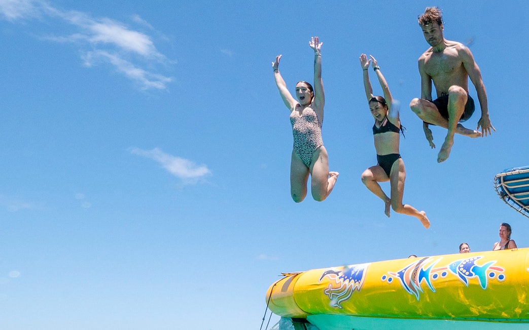 People jumping off a boat during Great Barrier Reef snorkel tour.