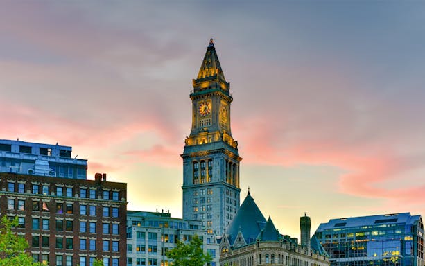 Custom House Tower in Boston at sunset with surrounding buildings.