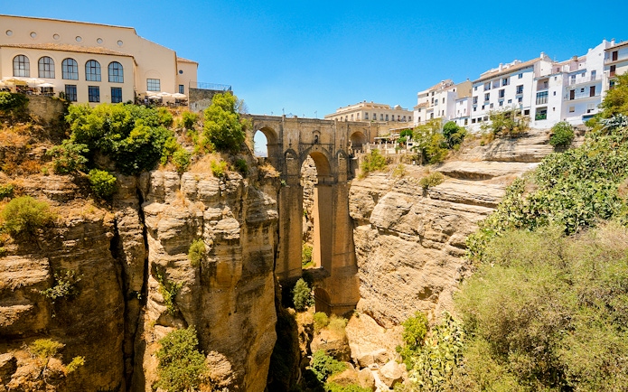 New Bridge spanning the El Tajo gorge in Ronda, Spain, with surrounding cliffs and buildings.
