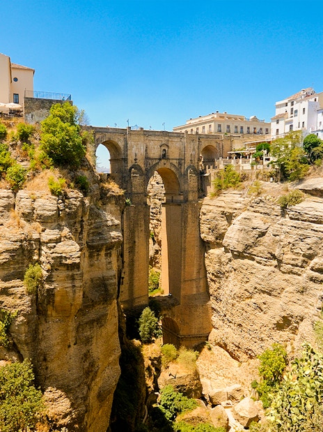 New Bridge spanning the El Tajo gorge in Ronda, Spain, with surrounding cliffs and buildings.