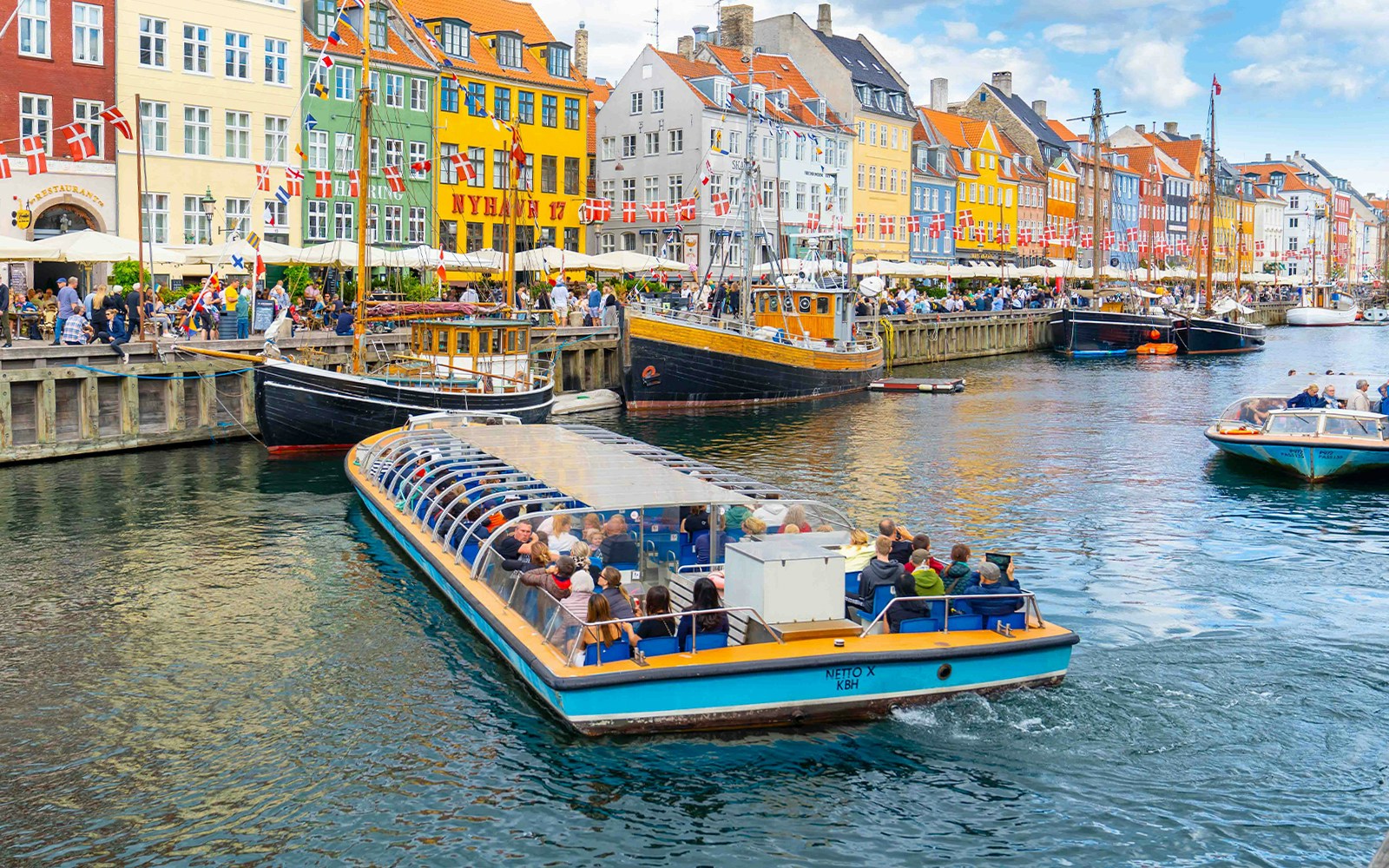 Copenhagen canal tour boat passing colorful Nyhavn waterfront buildings.