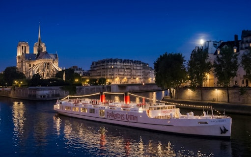 Dinner cruise boat on the Seine River with Notre-Dame Cathedral in the background, Paris.