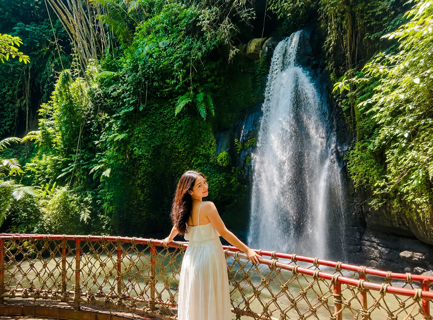 Person standing on a bridge near a waterfall in Ubud, Bali.