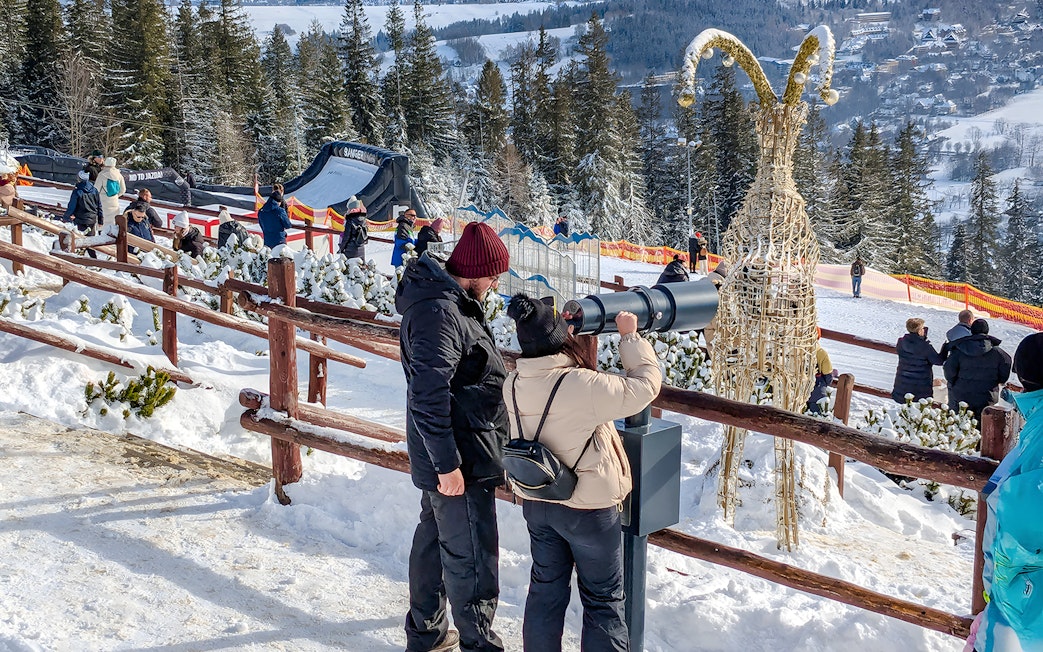 Couple using telescope at Gubałówka with Tatra Mountains view, Zakopane.