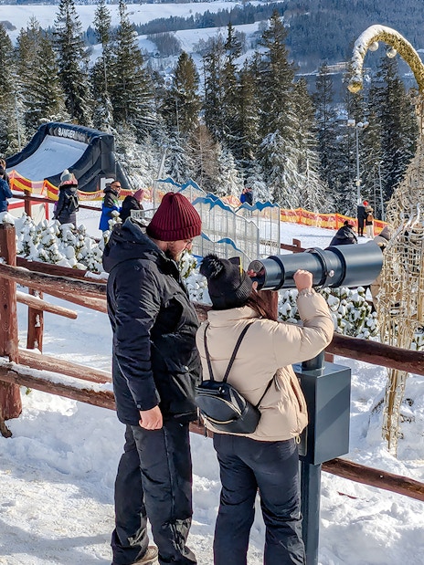 Couple using telescope at Gubałówka with Tatra Mountains view, Zakopane.