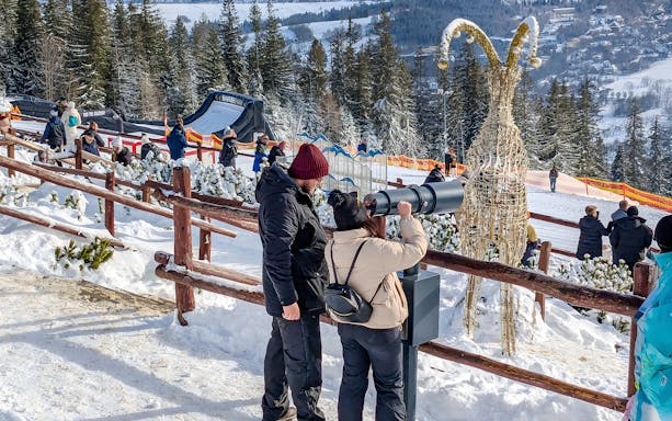 Couple using telescope at Gubałówka with Tatra Mountains view, Zakopane.