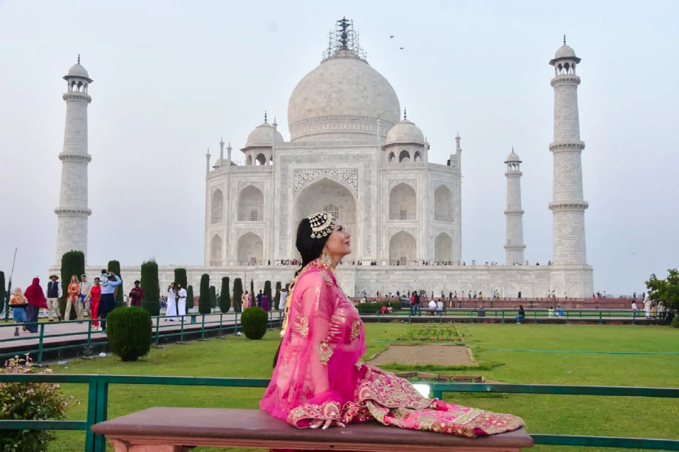 Person in traditional attire sitting in front of the Taj Mahal, Agra.