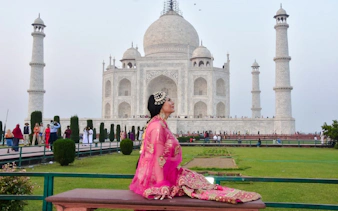 Person in traditional attire sitting in front of the Taj Mahal, Agra.