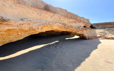 Rock formation at Pontal de Maceió beach, Fortim, with sandy ground and sunlight.