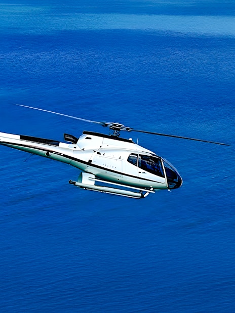 Helicopter flying over blue water in Dubai.