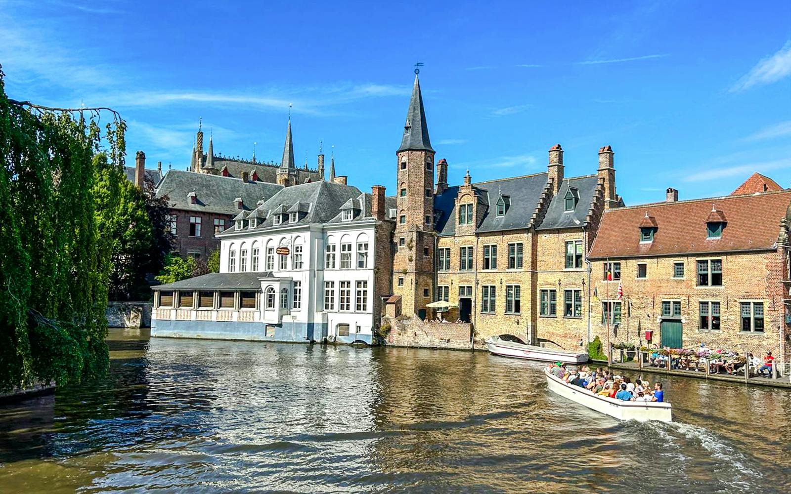 Boat tour on the canal at Rozenhoedkaai, Bruges, Belgium with historic buildings.