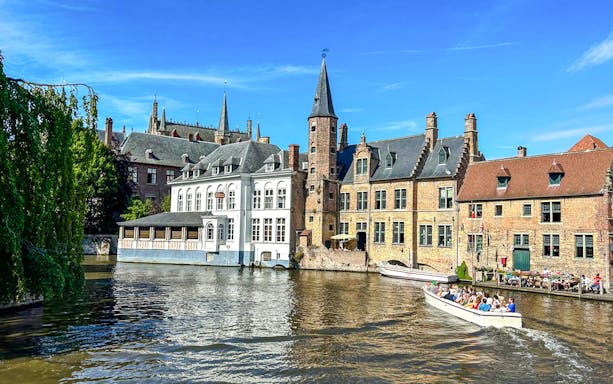 Boat tour on the canal at Rozenhoedkaai, Bruges, Belgium with historic buildings.