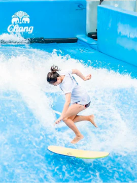 Person surfing on artificial wave at Flow House Bangkok.