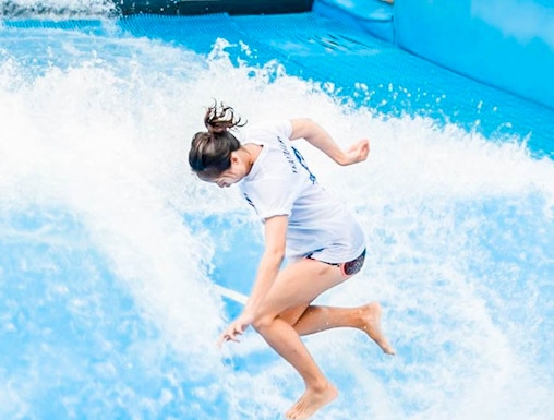 Person surfing on artificial wave at Flow House Bangkok.