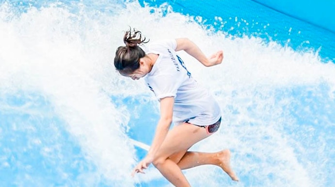 Person surfing on artificial wave at Flow House Bangkok.