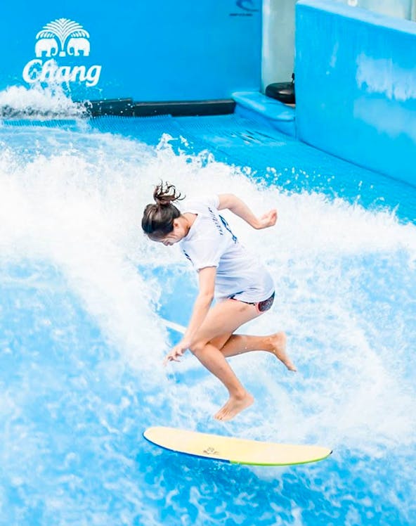 Person surfing on artificial wave at Flow House Bangkok.