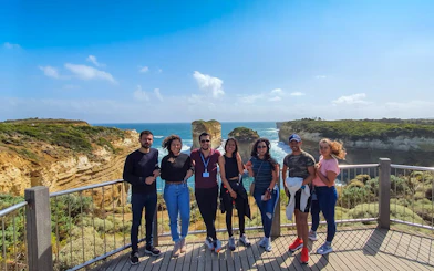 Group of tourists on a viewing platform overlooking coastal cliffs on the Great Ocean Road tour from Melbourne.