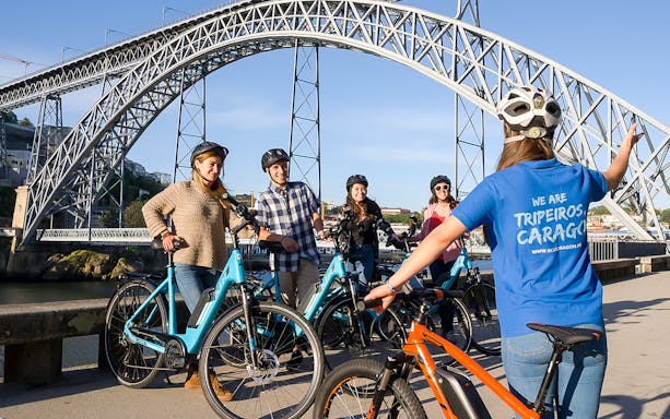 Group on bikes near a large bridge during a guided tour in Old Town and Riverside.