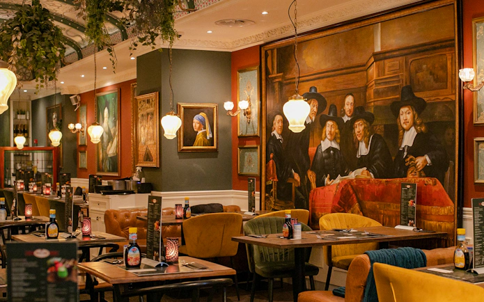 Dining area with Rembrandt-style paintings, Amsterdam brunch tour location.