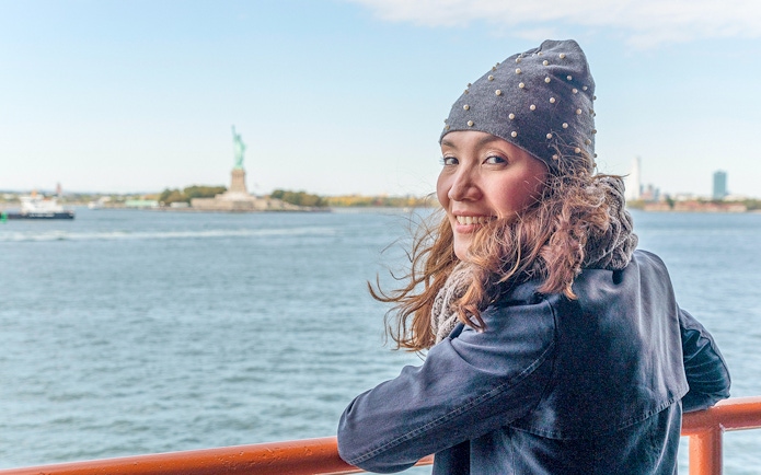 Person on ferry with Statue of Liberty in background, New York City.