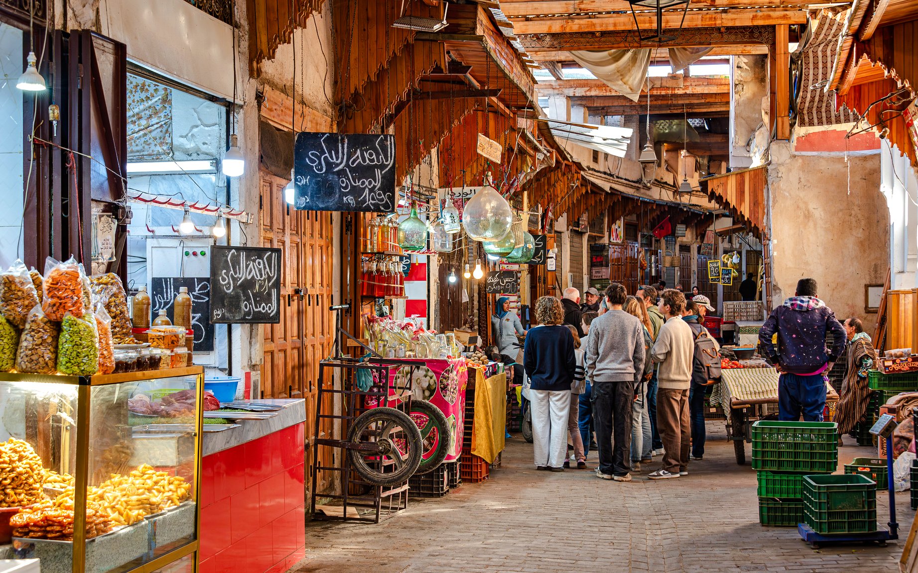 Visitors exploring vibrant stalls in Marrakech Souks, Morocco.