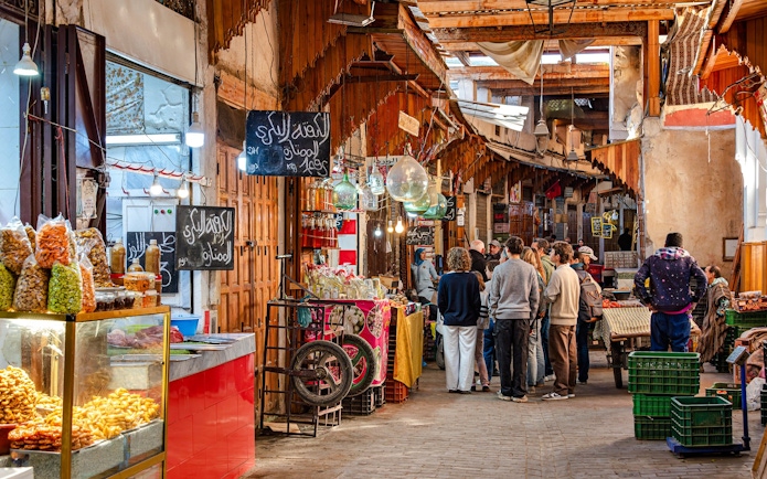 Visitors exploring vibrant stalls in Marrakech Souks, Morocco.