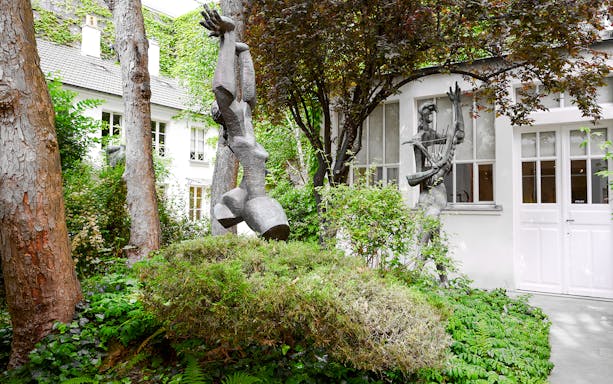 Sculptures in the garden of Zadkine Museum, Paris, surrounded by lush greenery.