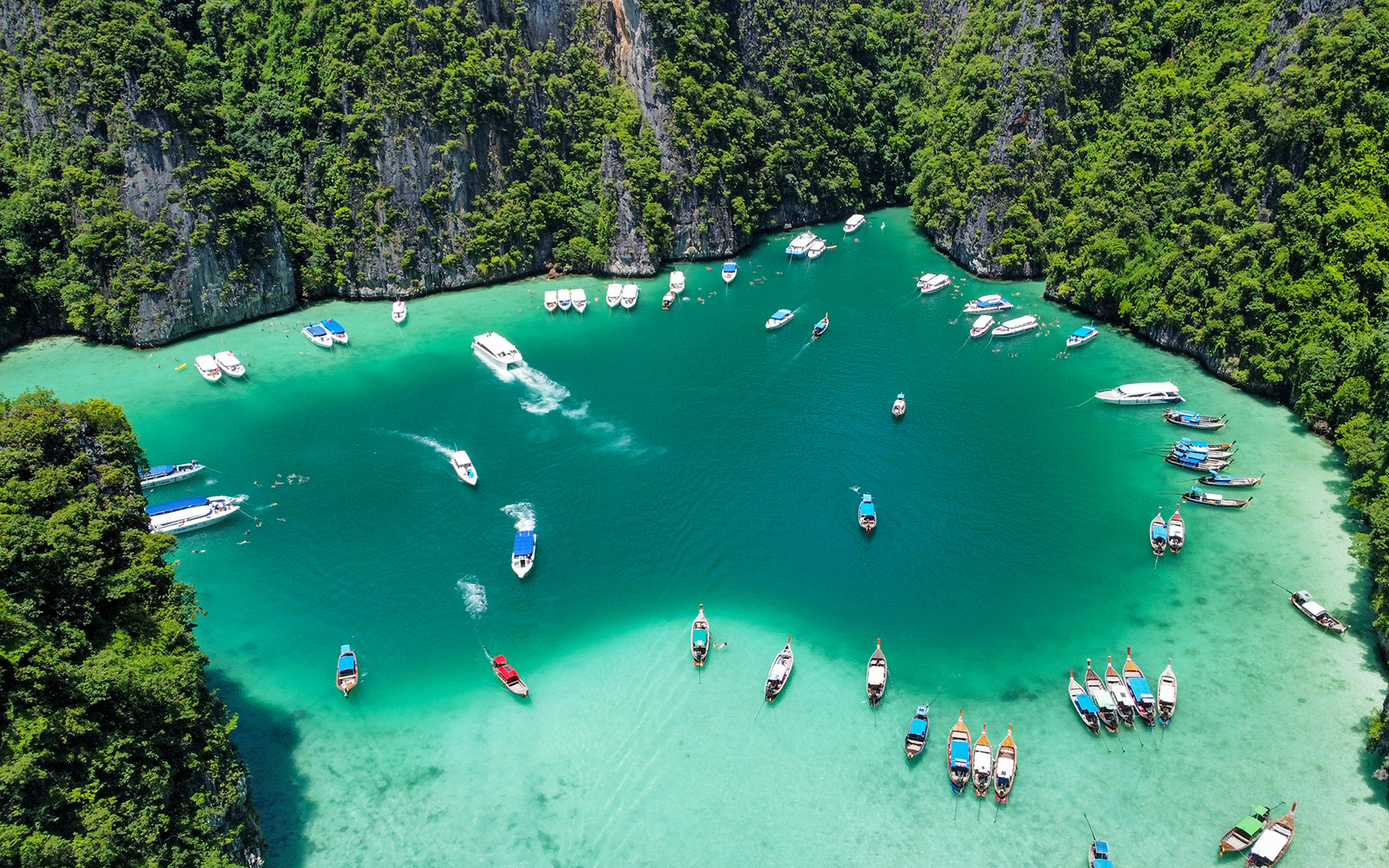 Speedboats and long-tail boats in turquoise waters of Phi Phi Islands, Thailand.
