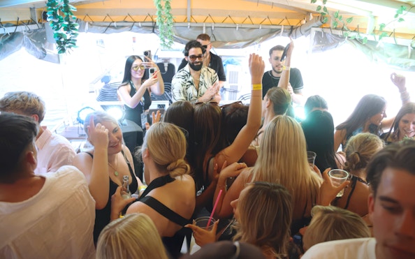 DJ performing on a boat cruise party in Prague with a lively crowd dancing.