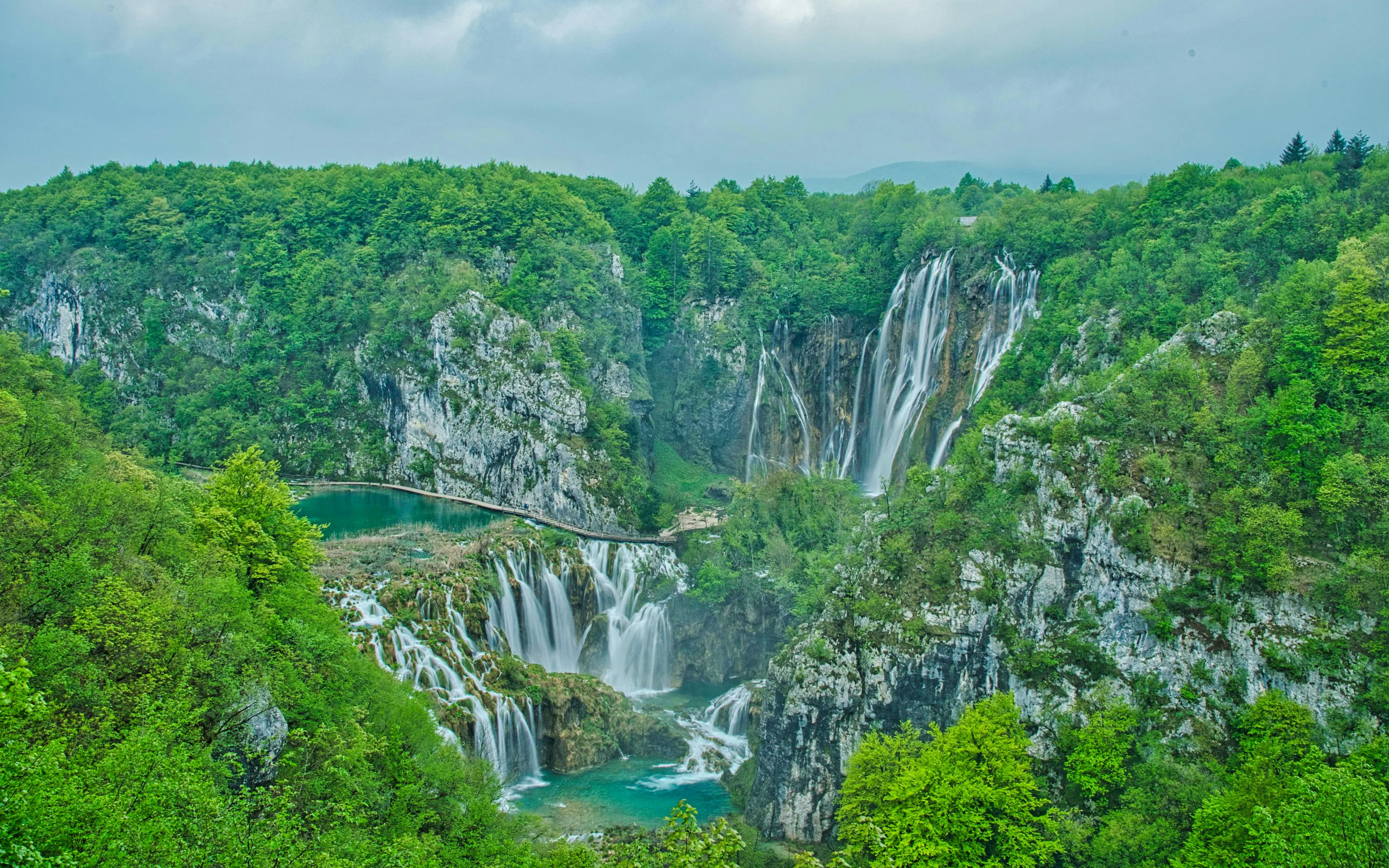Aerial view of Plitvice Lakes waterfalls surrounded by lush green forest in Croatia.