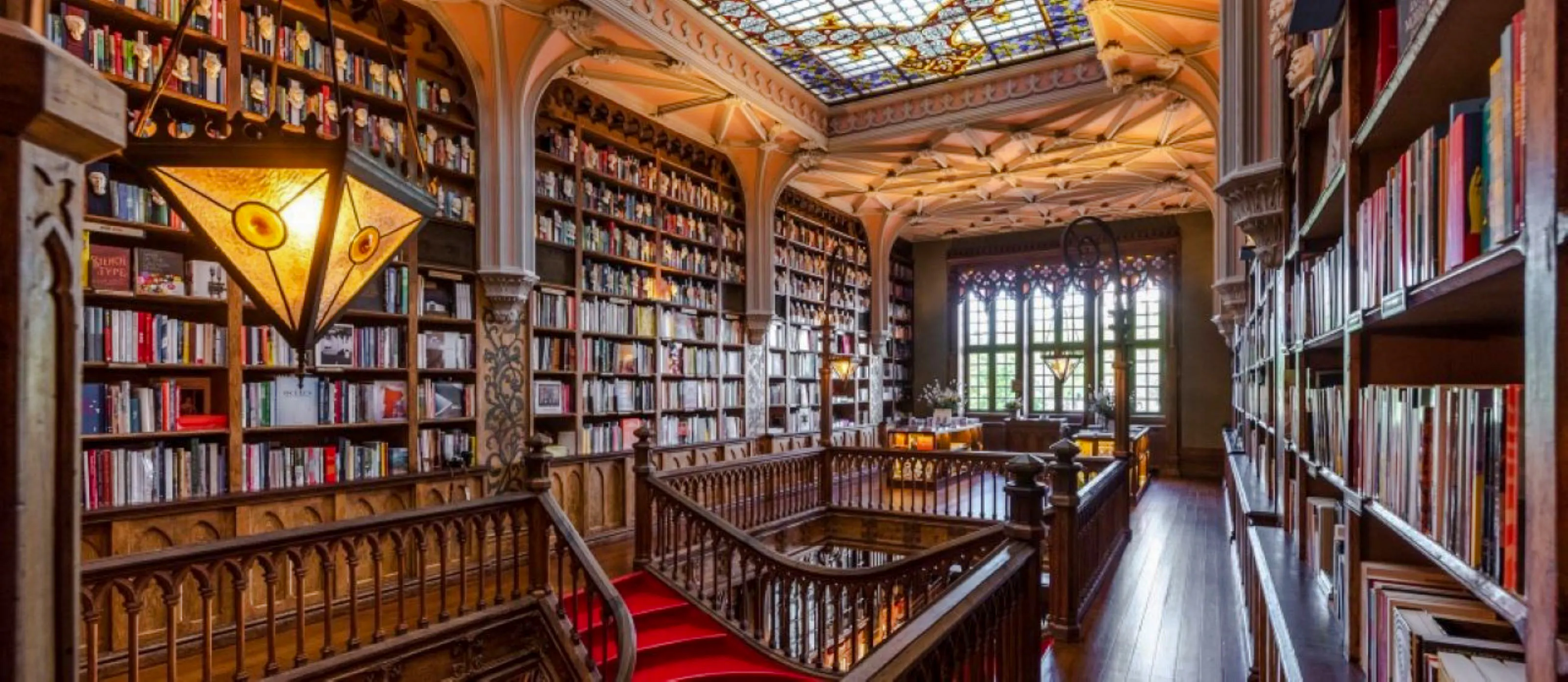 Livraria Lello interior with ornate wooden staircase and stained glass ceiling, Porto.