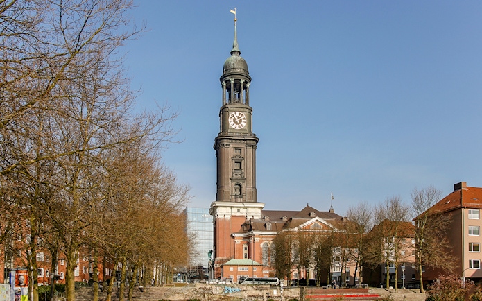 St. Michael's Church tower in Hamburg, view from a tree-lined street.