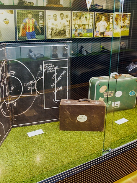 Valencia CF memorabilia display at Mestalla Forevertour, featuring vintage football tactics board and suitcases.