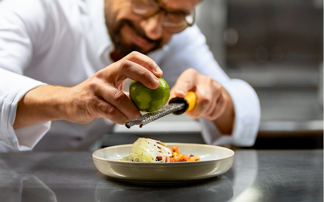 Chef zesting lime over dish on Seine River lunch cruise, Paris.