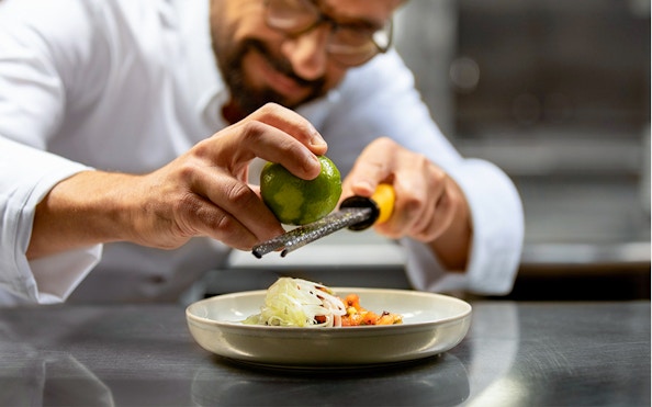 Chef zesting lime over dish on Seine River lunch cruise, Paris.