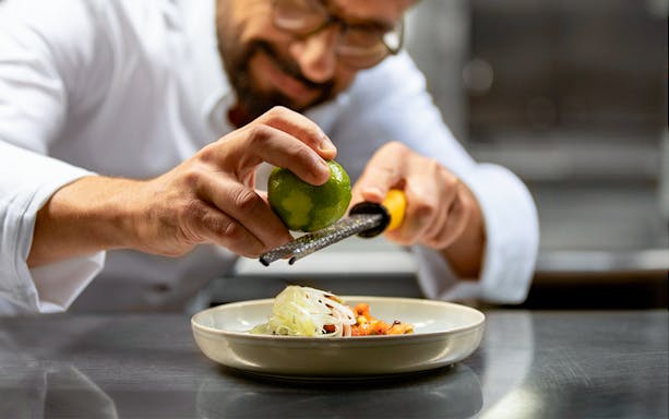 Chef zesting lime over dish on Seine River lunch cruise, Paris.