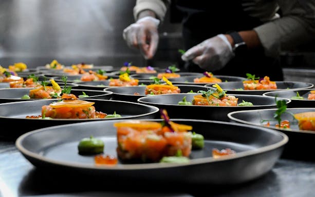Gourmet dishes being plated on Bustronome bus tour in Dubai.