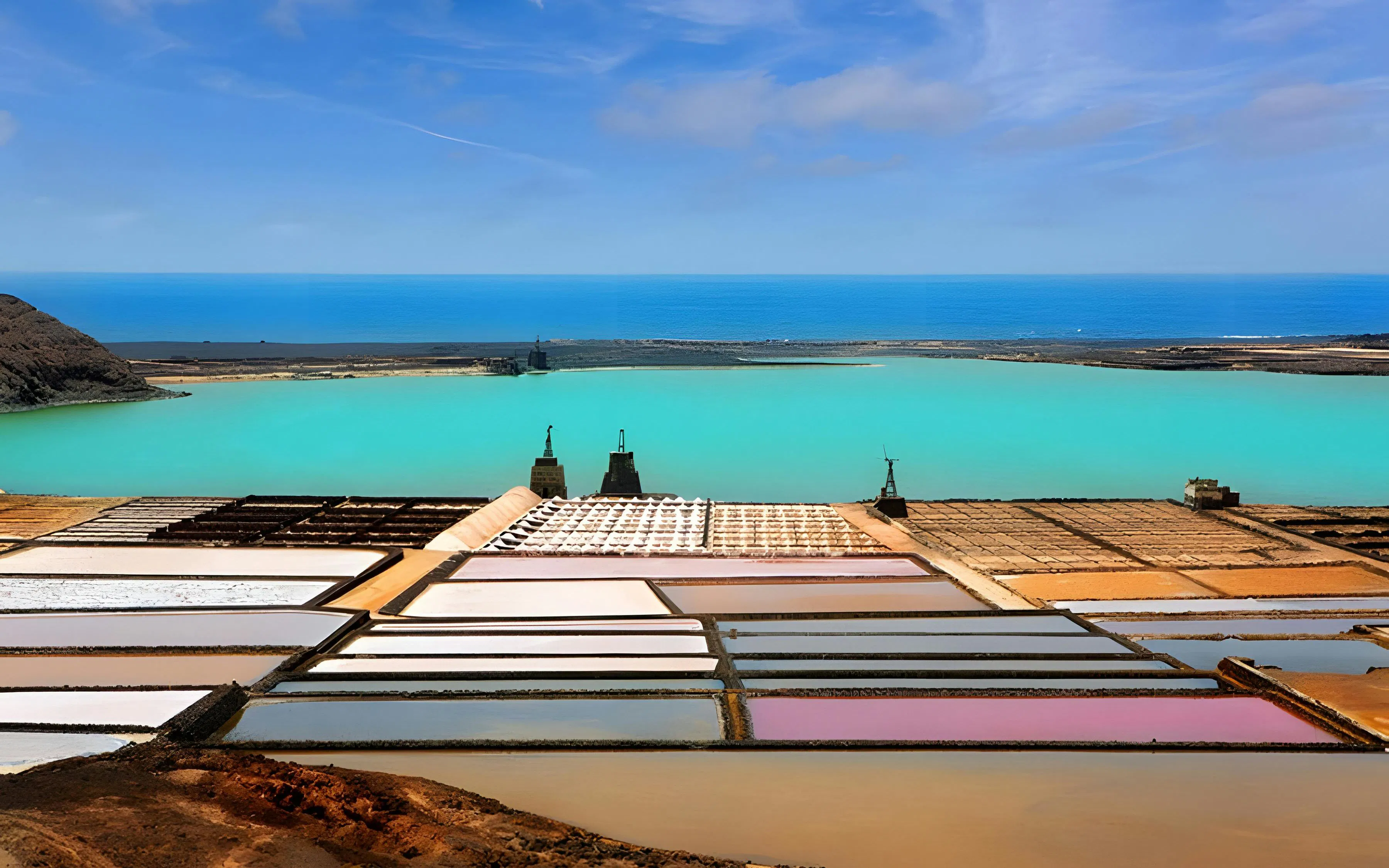 Salt pans at Salinas de Janubio, Lanzarote, with turquoise lagoon and ocean in the background.
