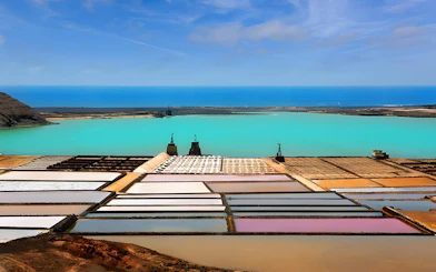 Salt pans at Salinas de Janubio, Lanzarote, with turquoise lagoon and ocean in the background.