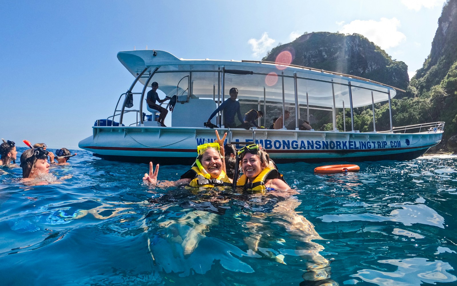 Tourists snorkeling near a boat in Nusa Lembongan, Bali.