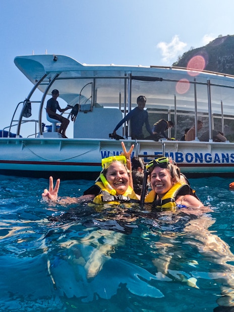 Tourists snorkeling near a boat in Nusa Lembongan, Bali.