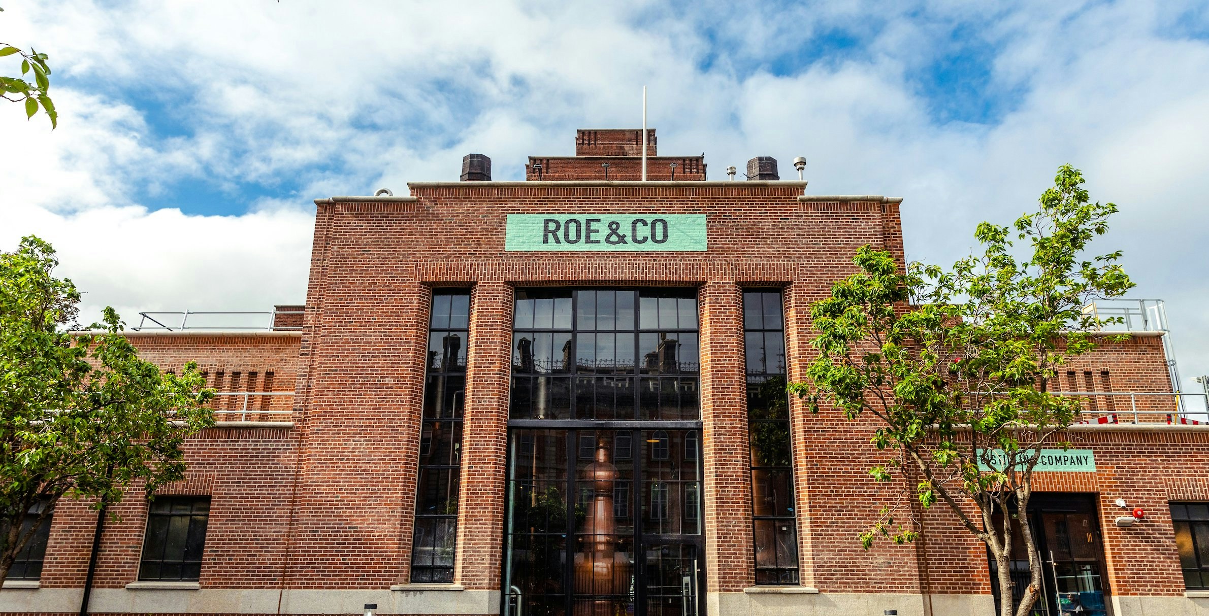 Roe & Co Distillery entrance with brick facade and trees in Dublin.