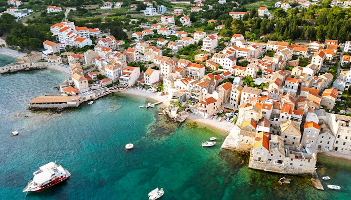 Aerial view of Komiza town with red-roofed buildings and boats in Vis, Croatia.