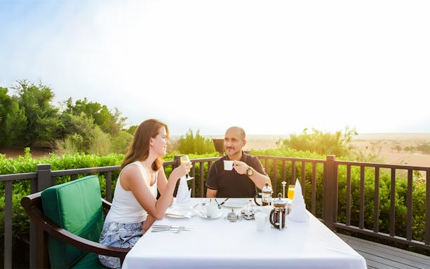 Tourists enjoying breakfast on a terrace with a desert view.
