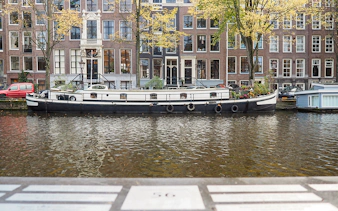 Canal boat on Amsterdam canal with historic buildings in the background.