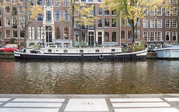 Canal boat on Amsterdam canal with historic buildings in the background.