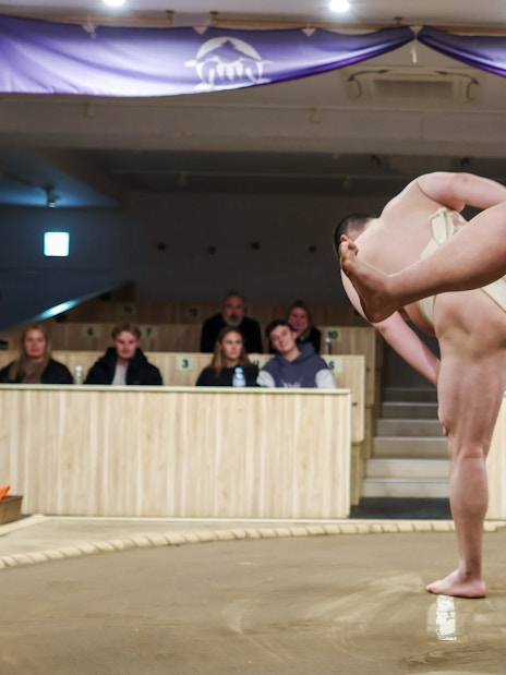 Sumo wrestlers performing in a Tokyo arena with spectators watching.