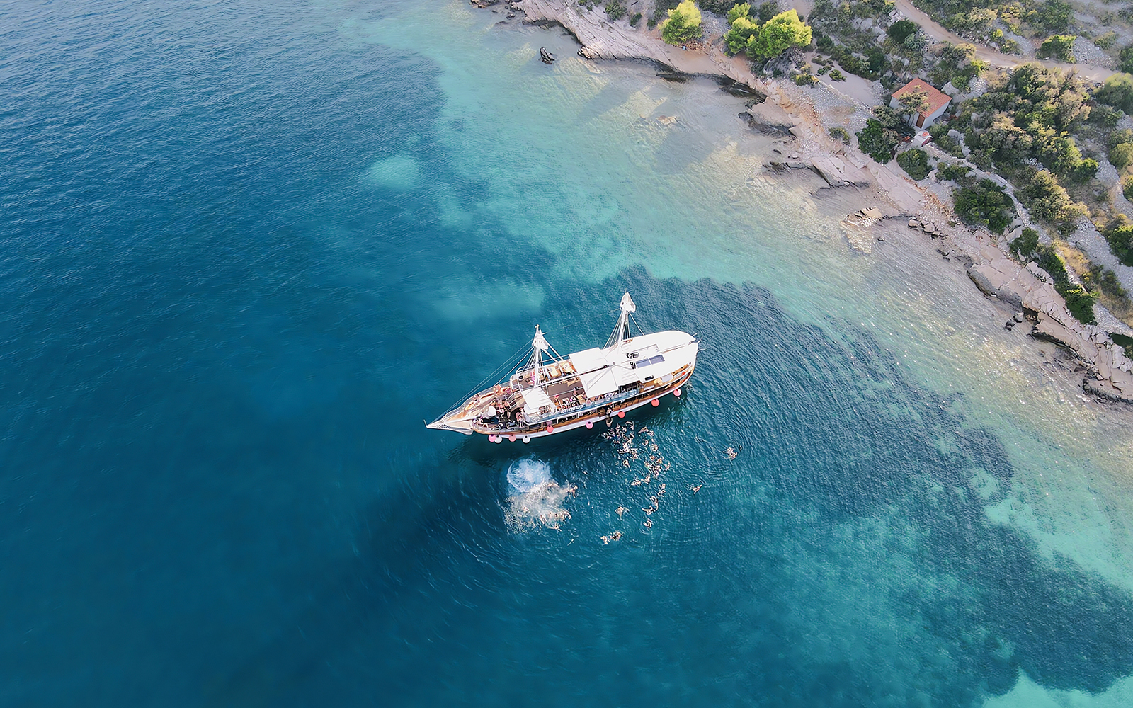 Boat party at Blue Lagoon, Split, Croatia with people swimming nearby.