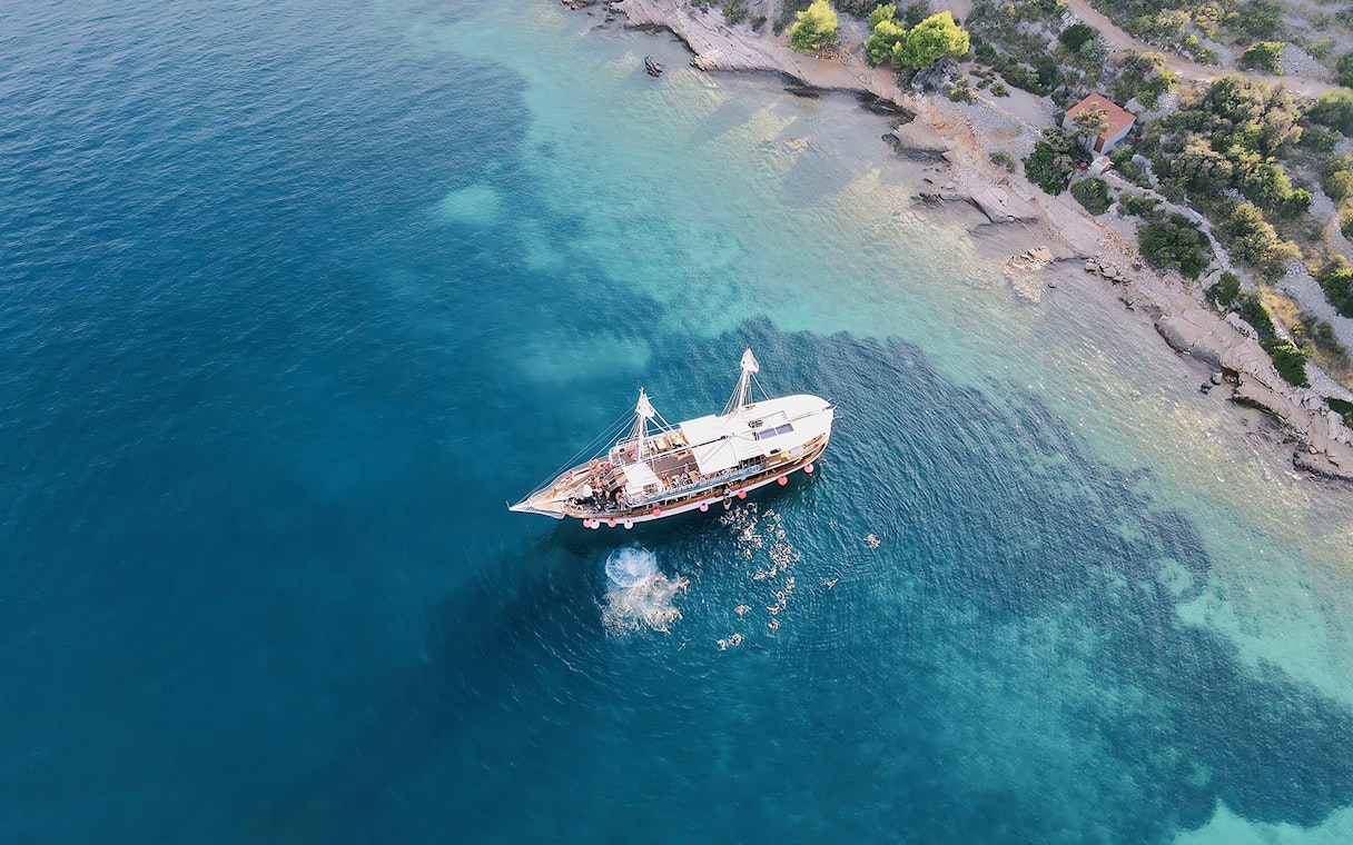 Boat party at Blue Lagoon, Split, Croatia with people swimming nearby.